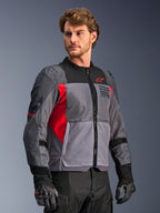 Veste Alpinestars St-2 Air, veste de moto, gris foncé et gris anthracite avec accents rouge vif, dotée de larges panneaux de ventilation en maille, de détails perforés au laser et d'un logo étoile rouge, portée par un mannequin en studio, style touring d'aventure moderne