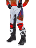 Alpinestars Pantalon Racer Hoen Junior 2024, pantalon de motocross, gris clair avec accents orange vif et noirs, avec logos étoiles rouges sur les cuisses et panneaux rouges aux genoux, porté avec des bottes noires et blanches, conception durable pour le tout-terrain