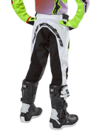 Pantalon Alpinestars Racer Lucent Junior 2024, pantalon de motocross, blanc et noir avec accents néon, vue arrière montrant le grand panneau extensible et le logo Alpinestars, porté avec des bottes Alpinestars Tech Series noires et blanches.