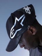 Alpinestars RSRV Resurgence Hat, casquette noire avec logo blanc audacieux, portée par une personne, design streetwear premium