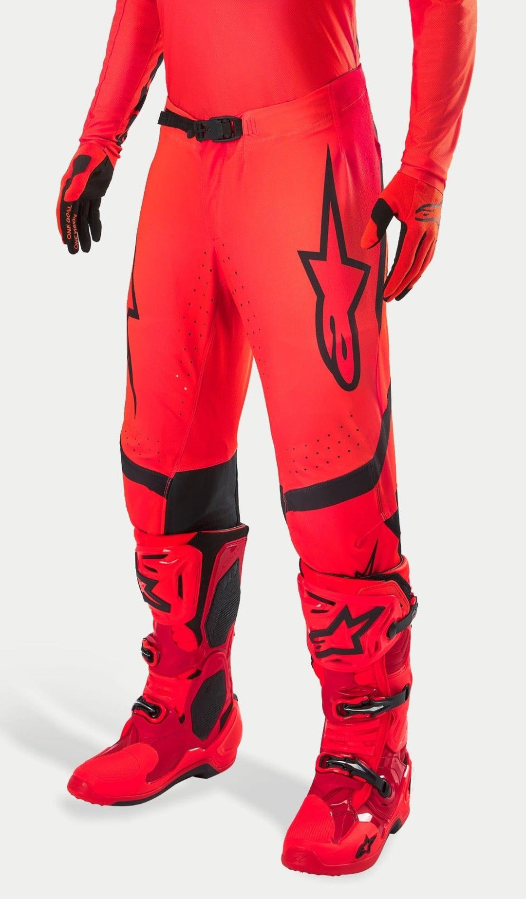 Pantalon de motocross Alpinestars Supertech Ember LE, rouge fluo et rouge vif avec accents noirs, porté avec des bottes et des gants de course rouges assortis, arborant un logo étoile noir sur la jambe, une boucle de taille sécurisée et des zones perforées pour la ventilation.