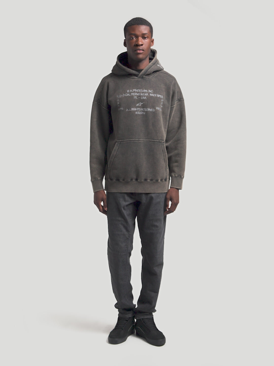 Alpinestars Infinite Washed Oversized Hoodie, Unisex Sportswear Pullover in Washed Black, featuring a premium snow-wash finish, front kangaroo pocket, and white embroidered brand wordmarks on the chest and hood for a vintage lifestyle look.